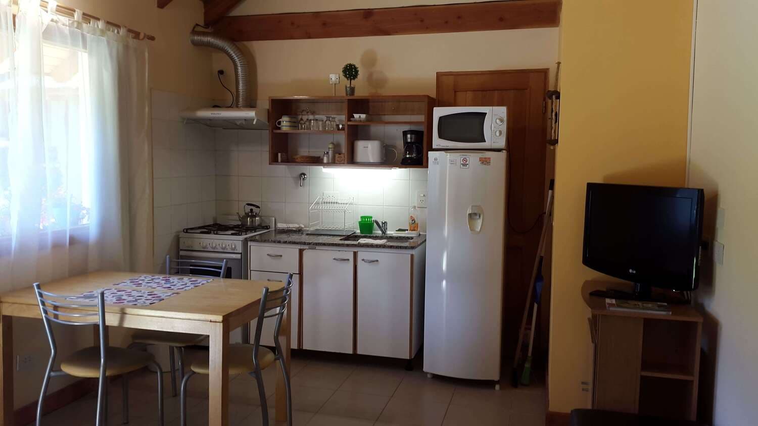 Kitchen, dining table, and TV of the monoambiente at Cabañas Denise